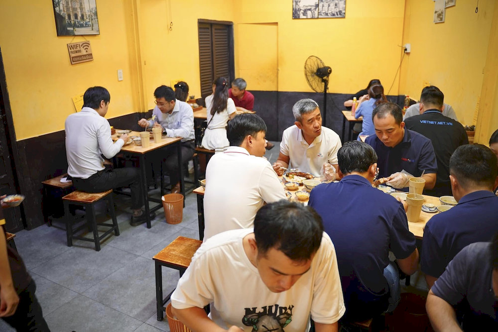 The small yet cozy space, with yellow walls and wooden furniture, captures the vintage spirit of old Saigon